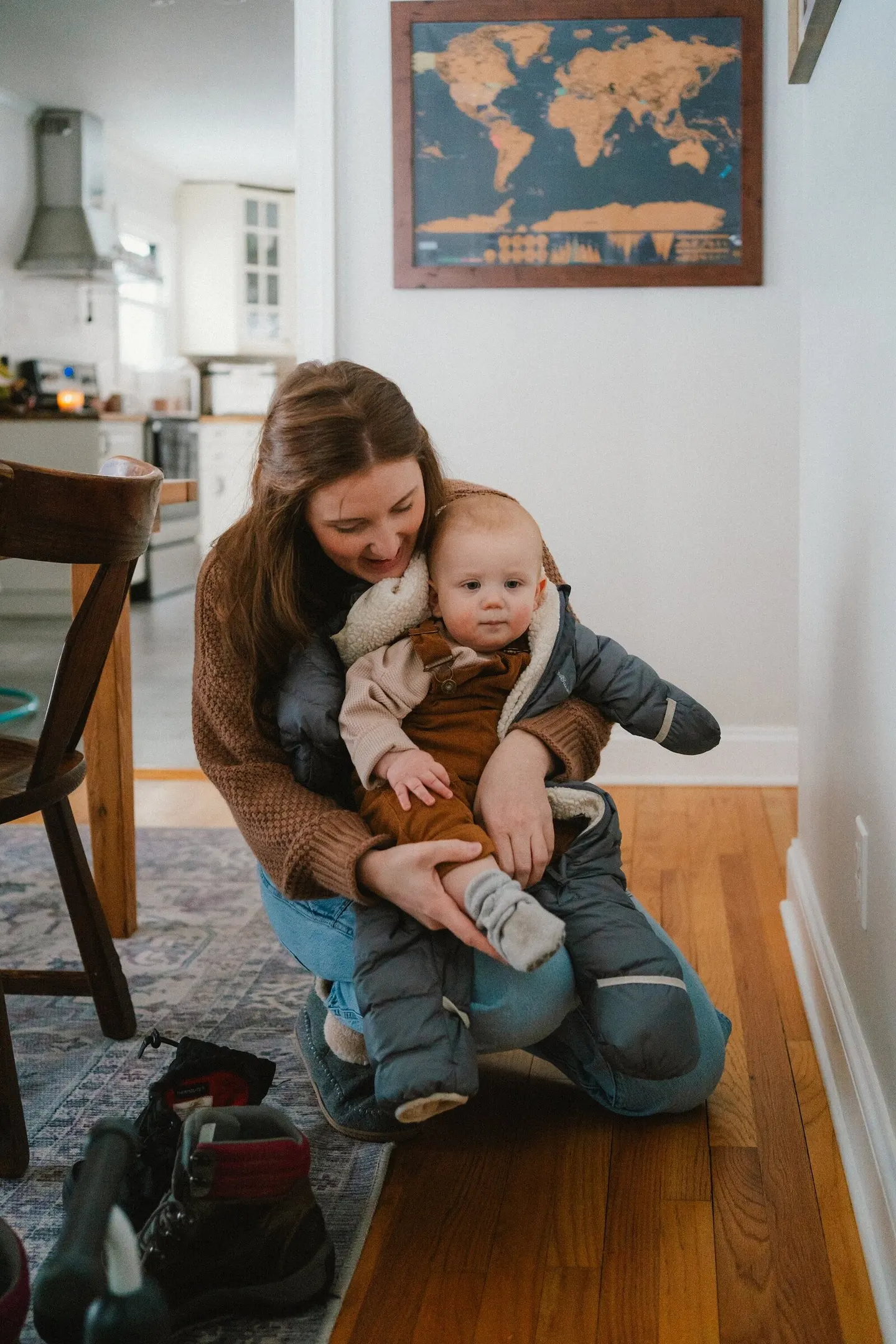 A Charlottesville family photographer finds a mother kneeling with her baby in a dim hallway lined with a world map.