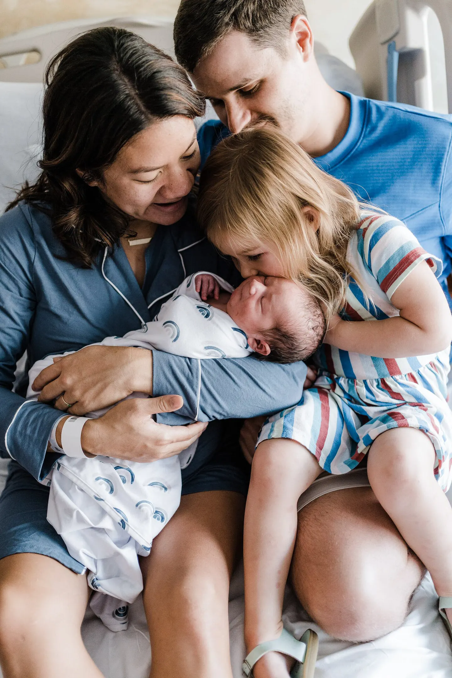 Mother holds twin infants on the porch while dad plays banjo for them