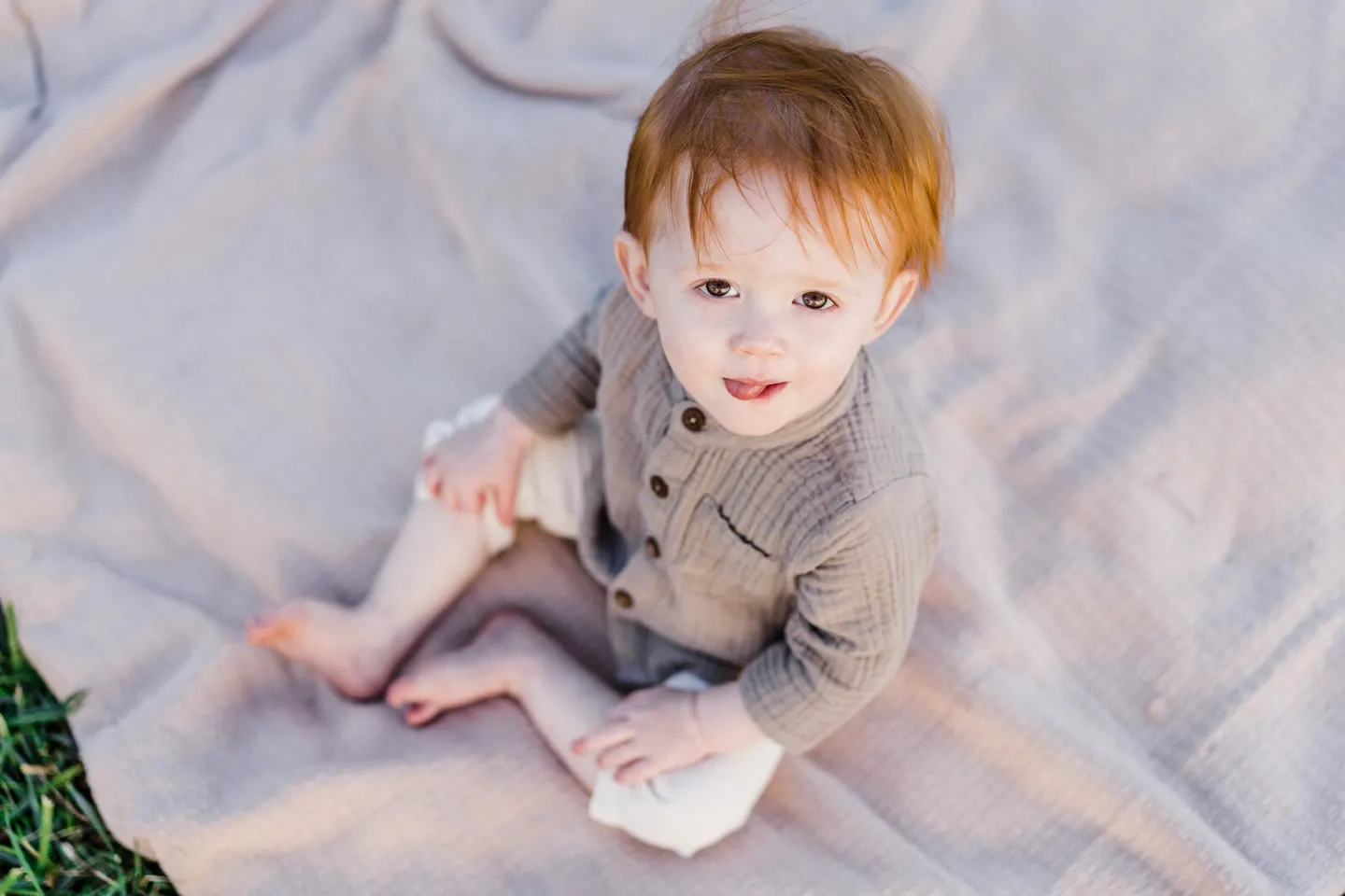 Toddler with copper hair sitting on a picnic blanket at Forest Lakes