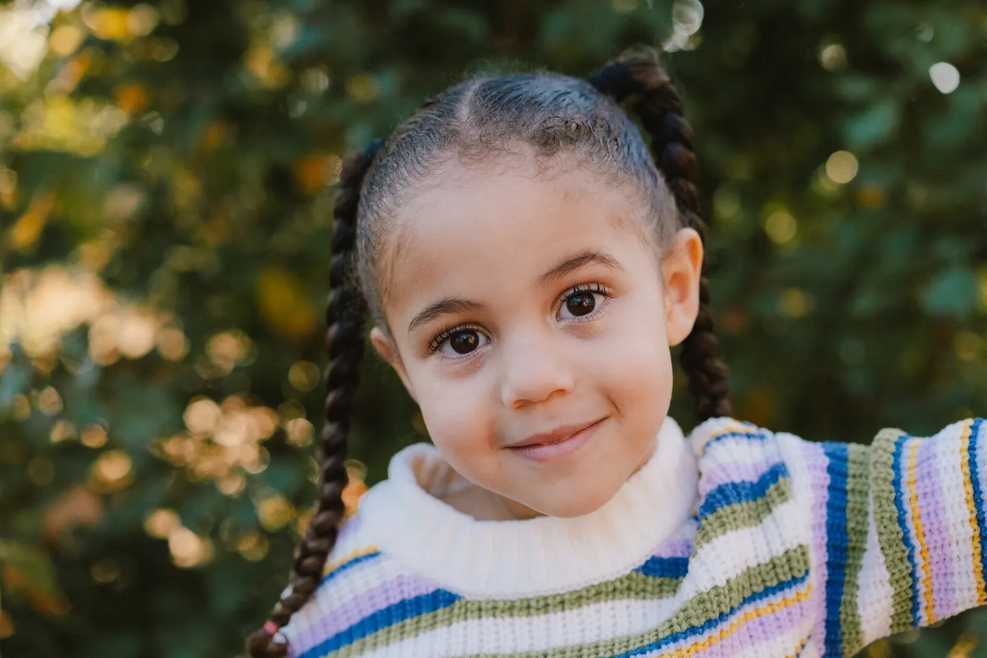 Girl with braided pigtails smiling in a striped sweater