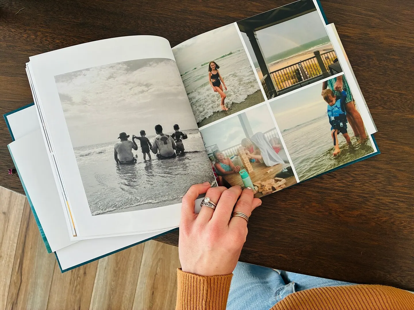 Hand holding open a printed photo book of beach vacation photos