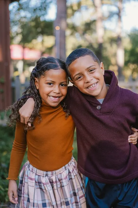 Siblings hugging in orange and maroon sweaters on school photo day