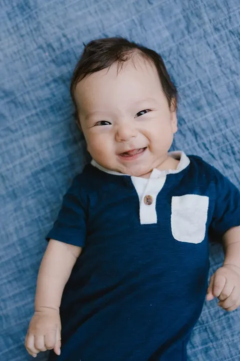 Redheaded baby boy sticking out his tongue on a picnic blanket at school photos