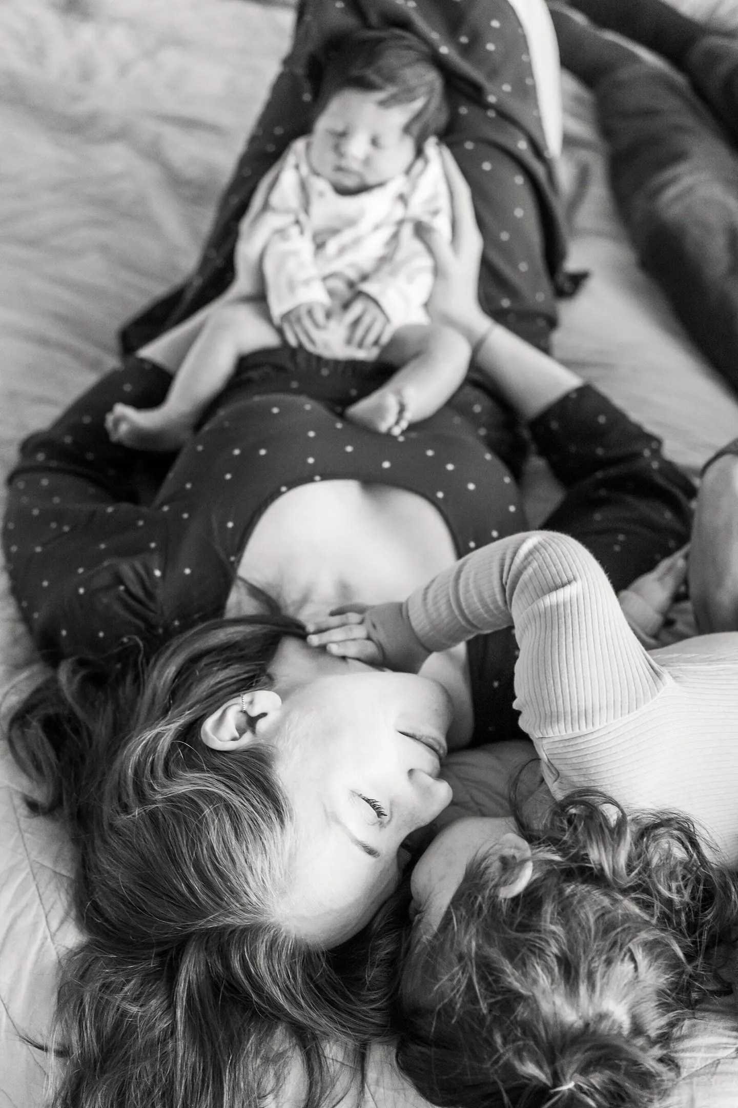 Mother and newborn lie face to face in black and white, baby propped on her chest
