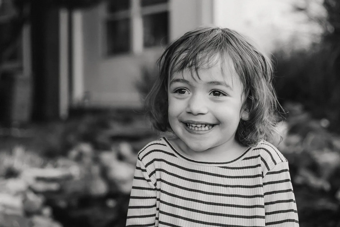 Black-and-white close-up of a curly-haired boy's gap-toothed smile