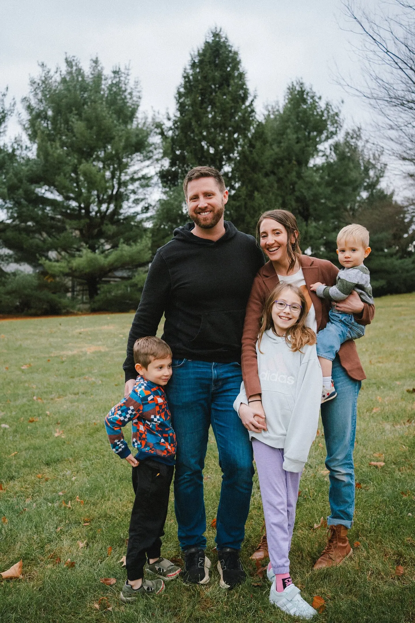 Leah's family of five smiling together in an open field