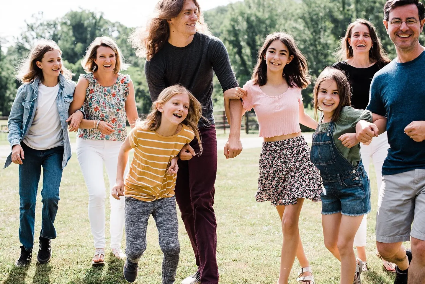 Charlottesville family photographer catches three generations strolling arm-in-arm across an open field.