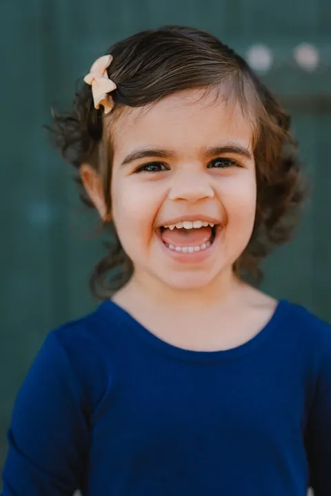 Girl laughing with her mouth wide open, hair clip catching the light