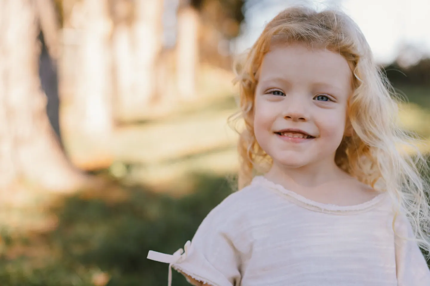 Curly-haired girl smiling in golden backlight at Frost Montessori