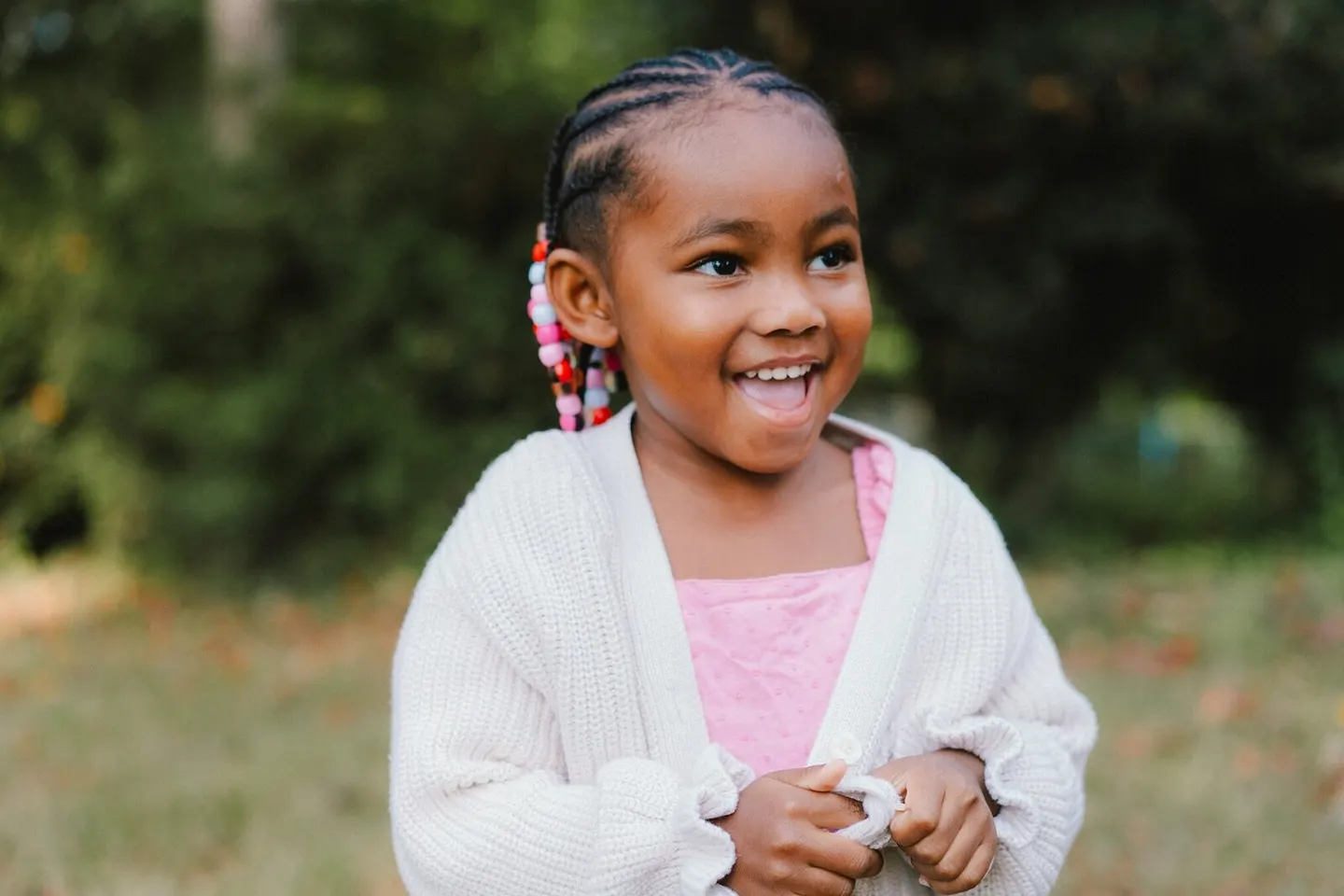 Preschooler with beaded braids grinning on the playground at Park Street Preschool