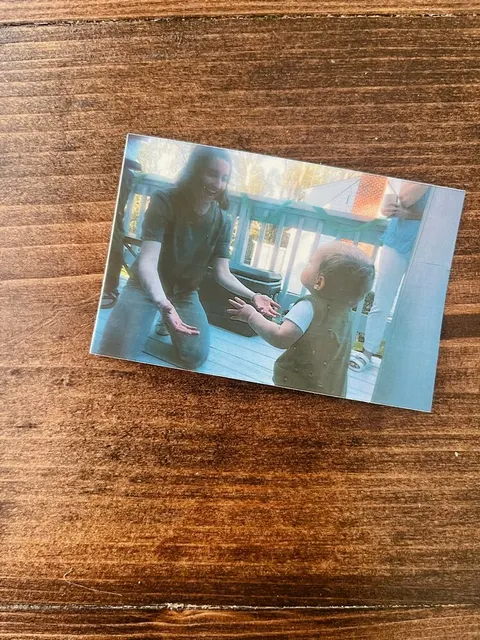 Faded photo of Leah kneeling to greet her toddler on the back deck