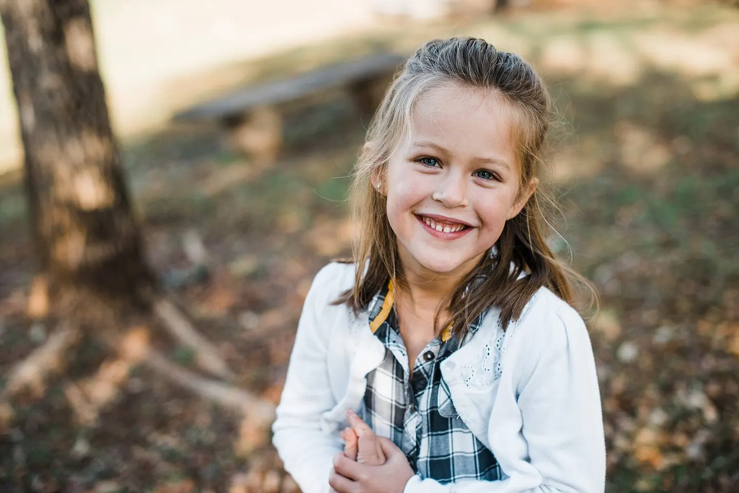 Girl in a white cardigan smiling in the woods at Free Union